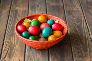 Obraz na płótnie Canvas Red wicker basket with colored Easter eggs on a wooden table