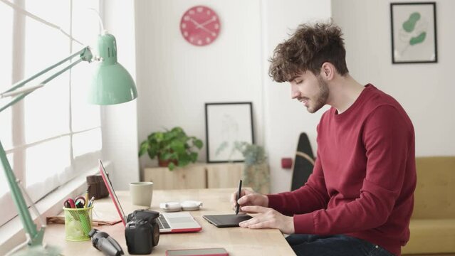 Hipster young adult graphic designer sketching on tablet working from home office - Freelance worker and entrepreneur concept. High quality 4k footage