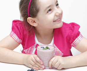 Young girl holding a glass of yoghurt and blueberry fruits