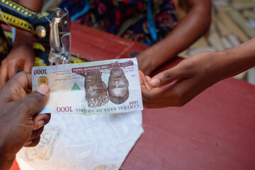 African hands exchanging cash, money or the Nigerian currency know as Naira in a tailoring shop for business purpose and with a sewing machine in the background