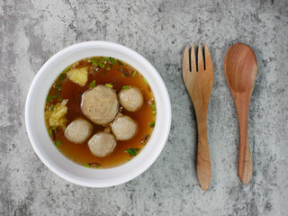 top view of beef meatballs in a white bowl with a wooden spoon and fork