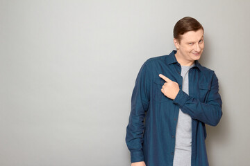 Portrait of happy charismatic man pointing with finger at copy space