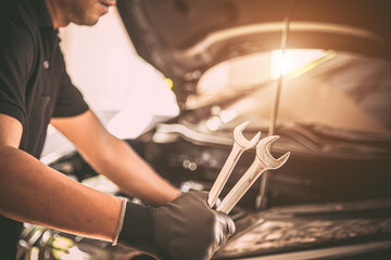 Close-up hand auto mechanic using the wrench to repairing car engine problem. Concepts of check and inspection car care maintenance and servicing.