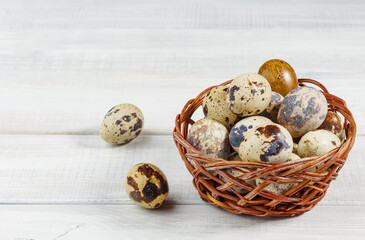 Fresh, farm, raw quail eggs in basket on white background. Two eggs lie on table.