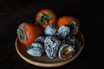 Dried persimmon and fresh persimmon on a wooden background. Healthy diet. Healthy diet