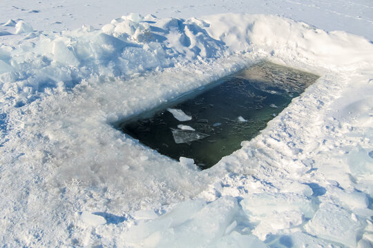 Ice hole in a frozen pond