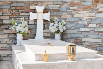 Orthodox Christian grave with a tombstone and a cross near the Greek temple.