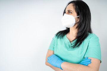 Nurse with face mask and blue medicine gloves crosses her arms and looks to the side