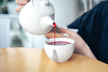 Close-up of a young woman pours tea from a teapot.