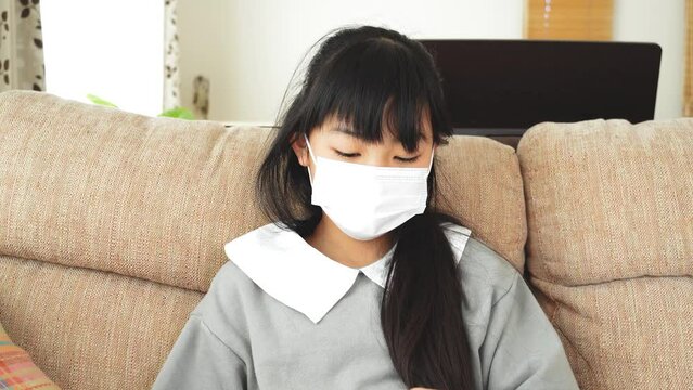 風邪を引いて体温を計る小学生の女の子
