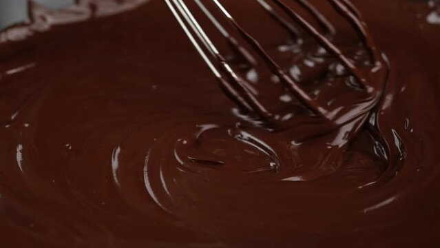 Melted chocolate close up. Stirring melted liquid chocolate with steel whisk. 4K UHD footage