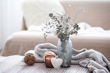 Home composition with a glass vase with dried flowers and a decorative heart.