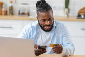 Happy African American using mobile phone and credit card for shopping online, smiling