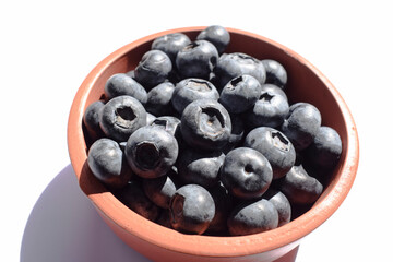 Heap o Blueberry fruits in a earthen bowl with white background. high in vitamin k, antioxidant, organic superfood blue berries.