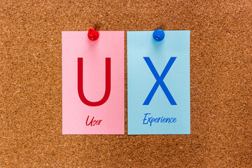 Conceptual 2 letters keyword UX (User Experience) on multicolored stickers attached to a cork board.