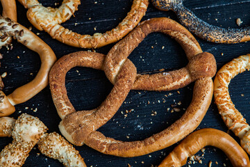 Fresh prepared homemade soft pretzels. Different types of baked bagels with seeds on a black background.