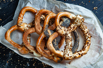 Fresh prepared homemade soft pretzels. Different types of baked bagels with seeds on a black background.