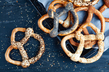 Fresh prepared homemade soft pretzels. Different types of baked bagels with seeds on a black background.