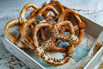 Fresh prepared homemade soft pretzels. Different types of baked bagels with seeds on a black background.
