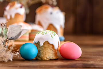 Festive cakes with white glaze, nuts and raisins with Easter eggs on the festive table