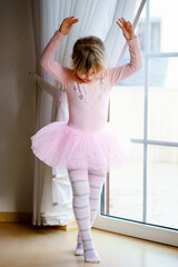 Little preschool girl dreams of becoming ballerina in a pink tutu skirt. Happy healthy child and ballet education, gymnastics for children.