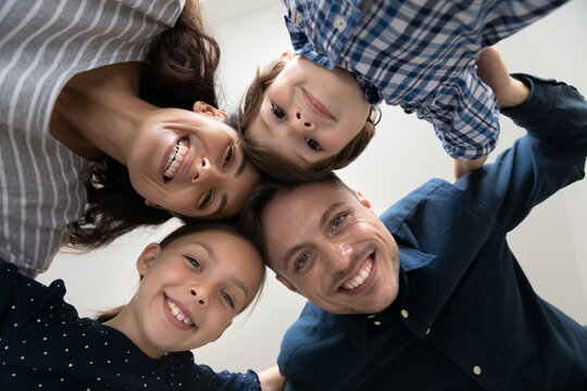 Close up low angle portrait of happy family with cute little kids looking at camera, smiling young mother and father with adorable 6s son and 8s daughter posing for funny picture together