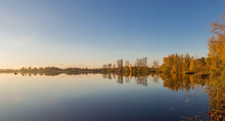 Naklejka na ściany i meble Panorama of autumn lake with setting sun and fisherman