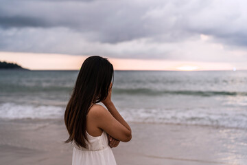 Young woman feeling lonely and sad looking at the sea on a gloomy day