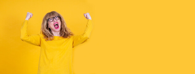 woman with arms raised as a sign of victory or achievement with copy space on yellow background