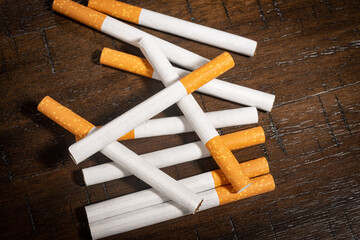 A small pile of loose cigarettes on a wooden table.
