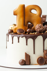 Birthday cake with chocolate drips decorated with chocolate cookies. Happy 18 years old. reaching age of majority. Gingerbread cookies with golden icing in the shape of digits one and eight.