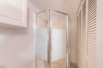 Small bathroom with corner shower stall with glass and aluminum frame