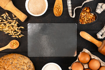 Making homemade sourdough bread loaf with rye flour, heart shape baking dish, rye ears, rolling pin, eggs, sourgough and cereal grains. Place for text at the middle of the picture. - Powered by Adobe