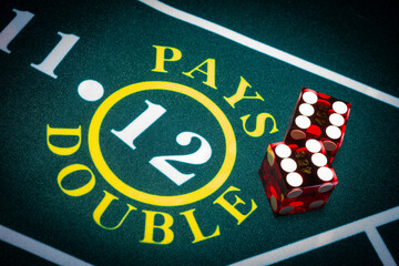 Professional casino-style dice sit on the field area of a craps table with text reading "12 pays double."