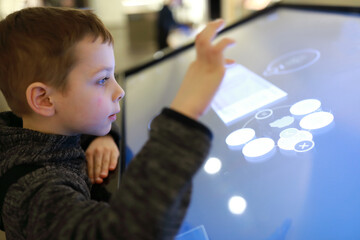 Boy playing puzzles on touch screen in entertainment center