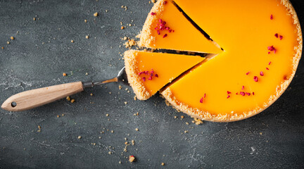 Flat lay of cheesecake with yellow mango flavoured layer decorated with red crumbs of freeze-dried...
