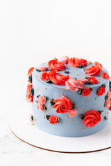 Birthday cake with blue cream cheese frosting decorated with red flowers on the white background