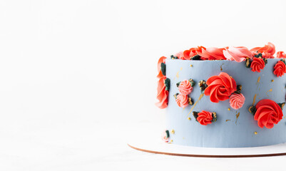 Birthday cake with blue cream cheese frosting decorated with red flowers on the white background