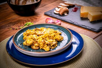 Saffron risotto with  mushrooms. Wooden table with garlic, cheese and mushrooms in the background