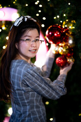 Asian women smile sweetly. Person are celebrating Christmas or New Years concept. Woman touching red ball Christmas. Vertical image.