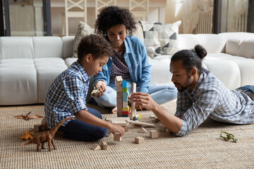Happy caring loving young African American couple parents playing wooden toys with small cute...