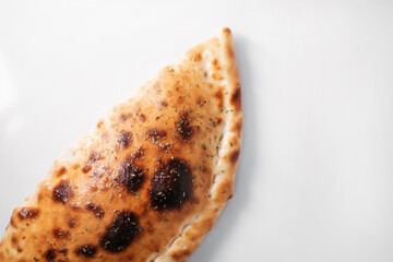 Italian pizza calzone on white table.