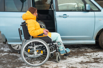 Caucasian woman in a wheelchair gets into the car. 
