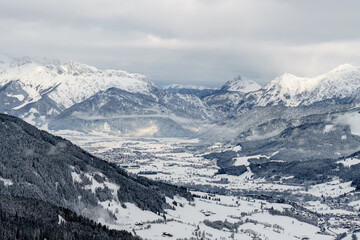Fototapeta premium View of the mountains and the town of Maria Alm am Steinernen Meer in Salzburg, Austria - Hochkönig region - Fog lies over the town