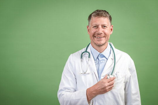 Middle Aged Male Doctor With Grey Hair Wearing Stethoscope And White Coat On Green Background