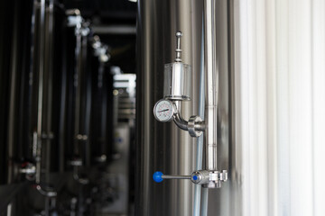 Pressure on pressure gauge on industrial machine in factory. Modern Beer Factory. Steel tanks for beer fermentation and storage.