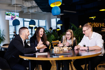 A company of colleagues in the office during a break plays the board game jenga. Fun board games for friends