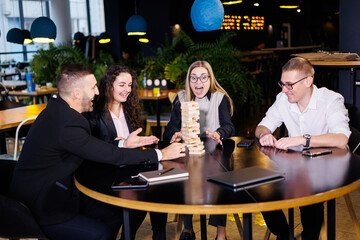 Businessmen play jenga. Business holiday concept. Young people play board games in the office