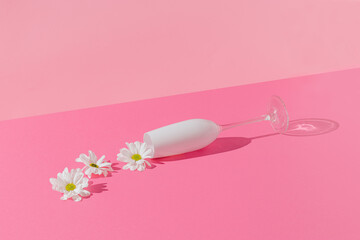 Creative composition with white flower spilling out of champagne glass on bright pink background. Minimal spring love or Mother's Day concept.