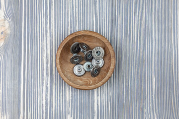 Metal buttons for jeans in a wooden bowl.
